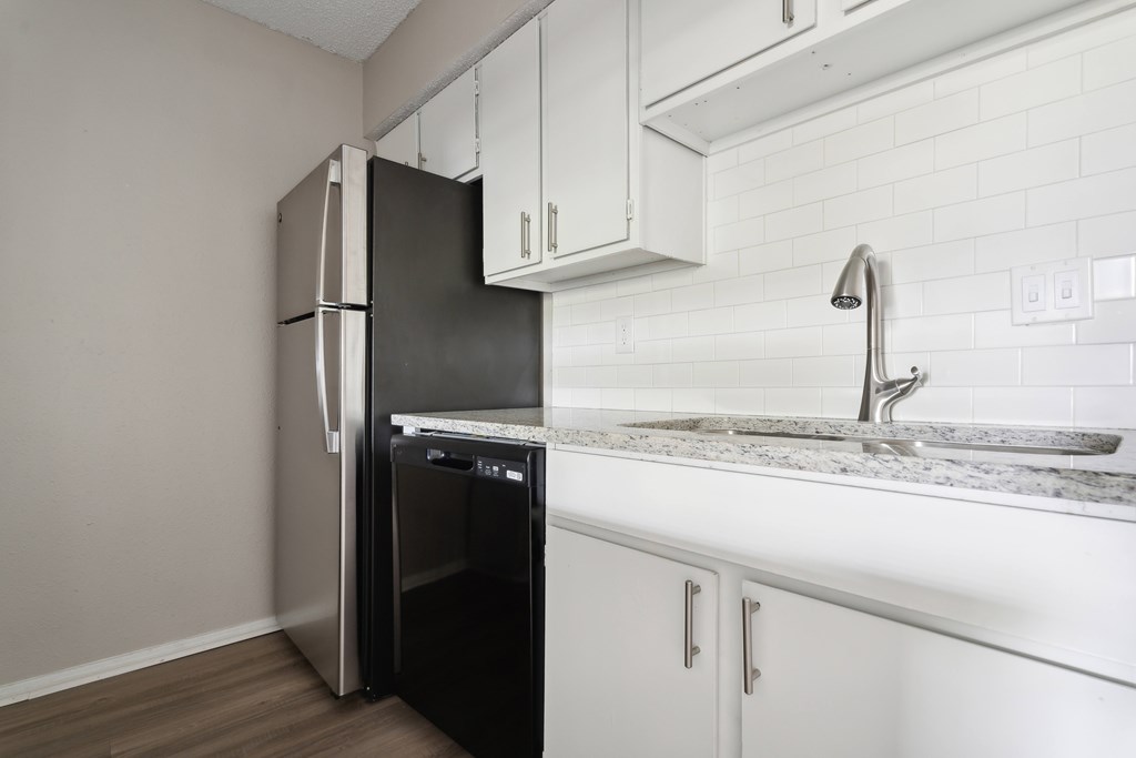 A black refrigerator is in a kitchen with white cabinets. at Anson at North Hills, Raleigh, NC