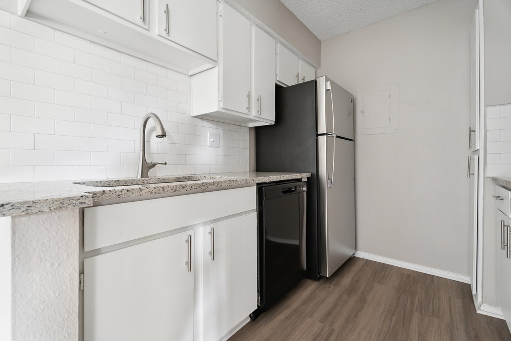 A kitchen with white cabinets and a black fridge. at Anson at North Hills, Raleigh