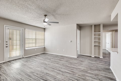 Empty living area with builtin shelves and wood flooring at The Meadows Apartments, Garland, TX 75043