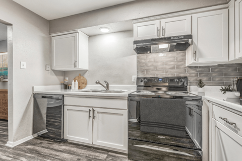 A modern kitchen with white cabinets and a black stove top oven.