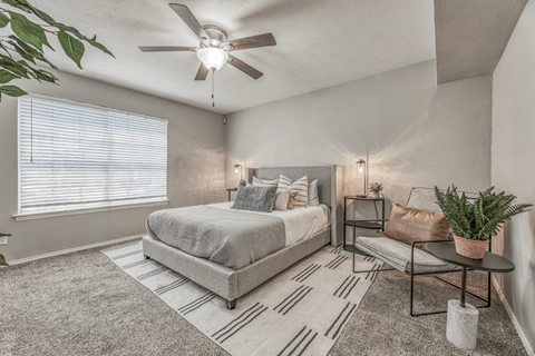 A bedroom with a bed, a chair, and a potted plant.