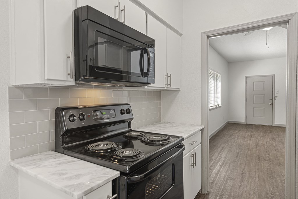 a kitchen with white cabinets and a black microwave and stove