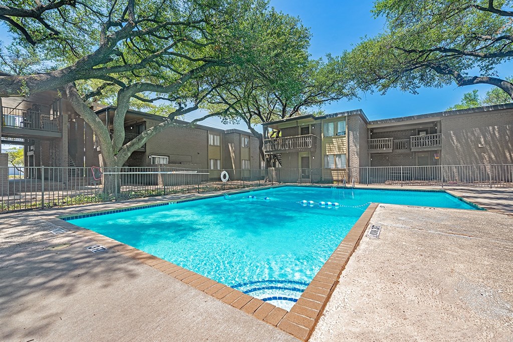a swimming pool with trees and apartments in the background