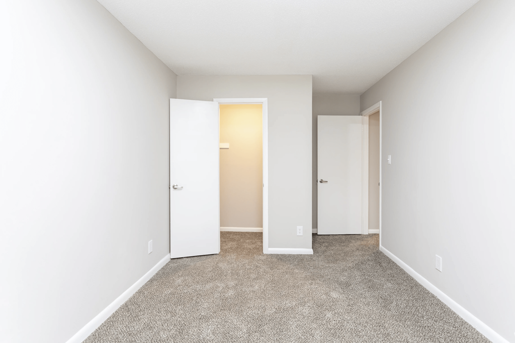 A room with a carpeted floor and two doors.