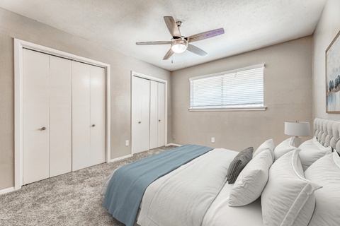 A bedroom with a bed, pillows, and a ceiling fan.