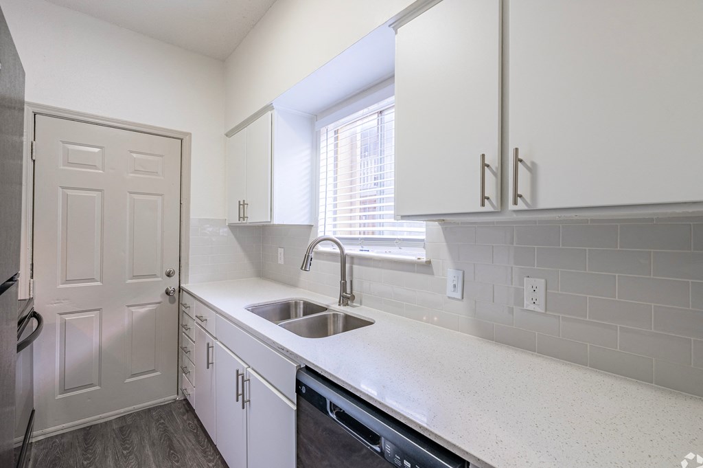 a kitchen with white cabinets and a sink and a window