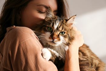 a woman holding a cat on her shoulder