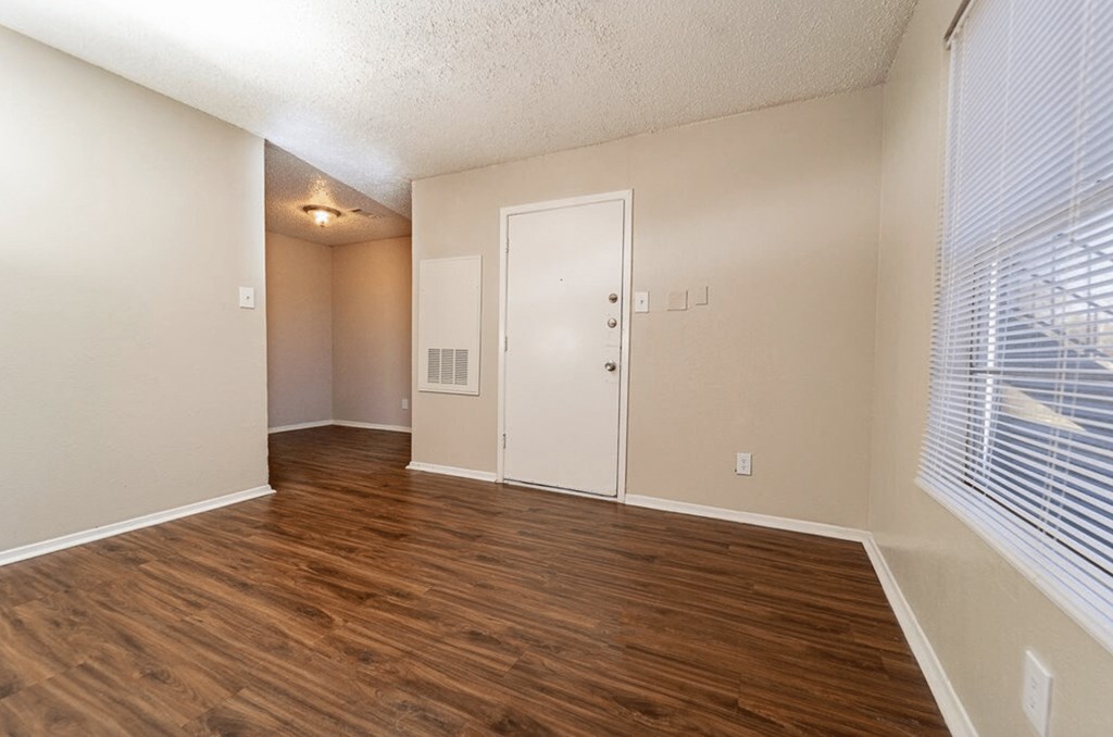 an empty living room with wood flooring and a window