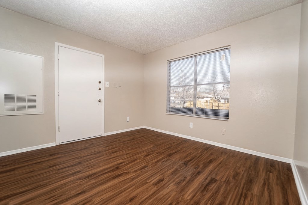 an empty living room with wood flooring and a window