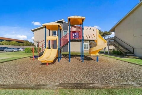 Playground area with slides and climbing structure at North Creek Apartments, Dallas