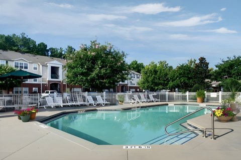 Outdoor pool with white lounge chairs and landscaped deck at Walnut Ridge Apartments, Raleigh, North Carolina