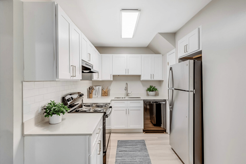 a white kitchen with white cabinets and a stainless steel refrigerator