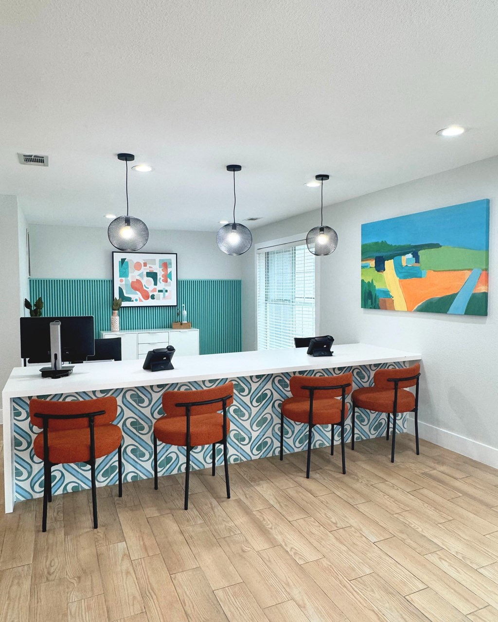 A white desk with a computer and two chairs in front of a blue and white patterned wall at Carisma in Richardson, TX