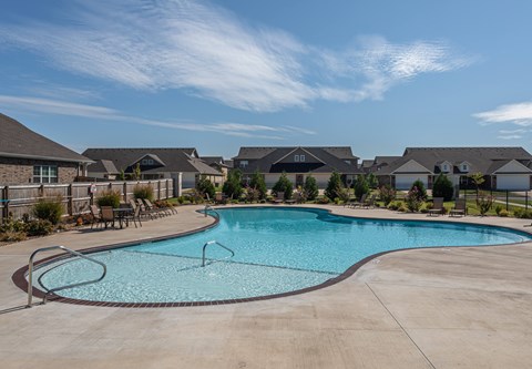 A large swimming pool in a residential area with houses in the background.