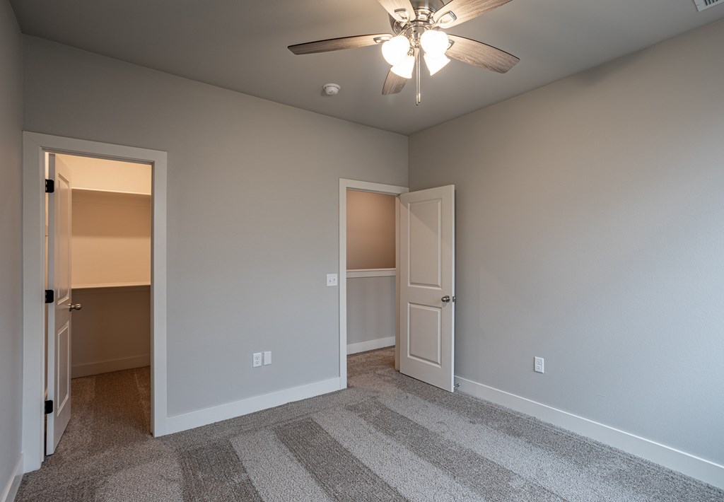 A room with a ceiling fan and two doors at Cedar Crest Apartments, Farmington 72730