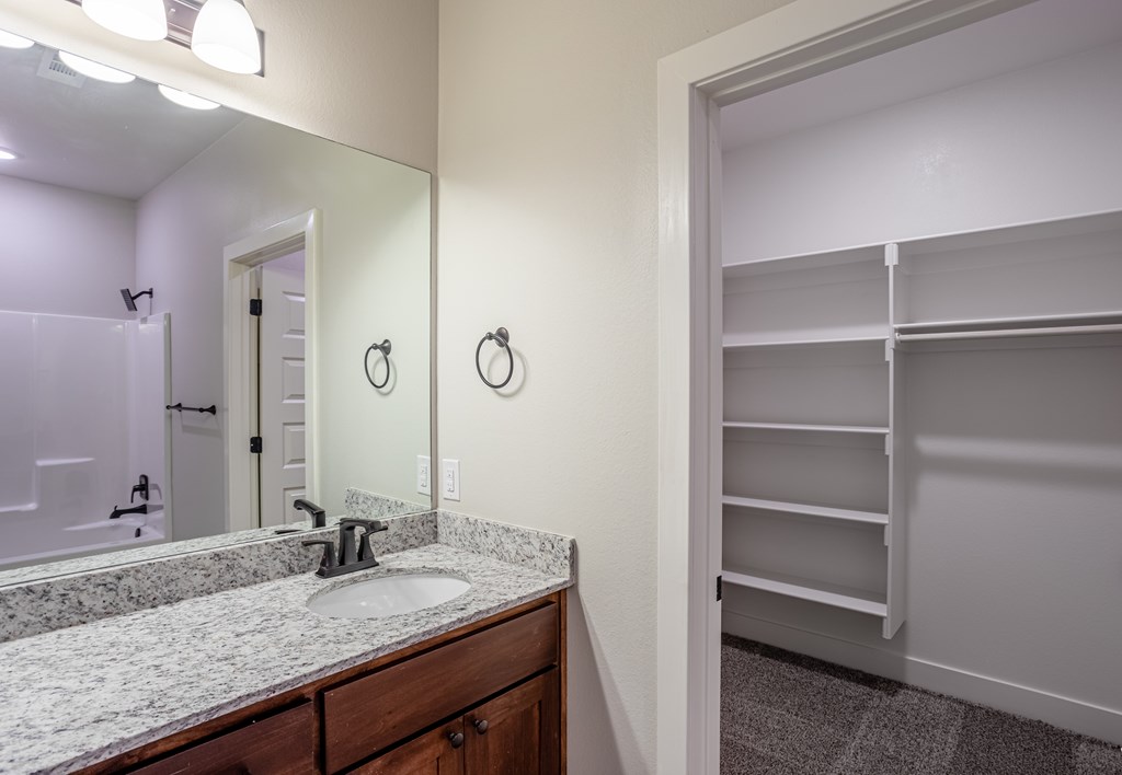 A bathroom with a sink, mirror, and a closet at Cedar Crest Apartments, Arkansas
