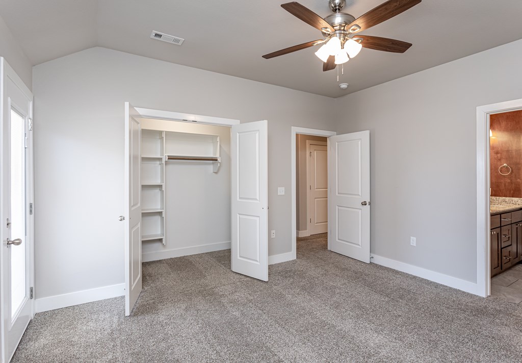 A room with a ceiling fan and a closet with shelves at Cedar Crest Apartments, Farmington