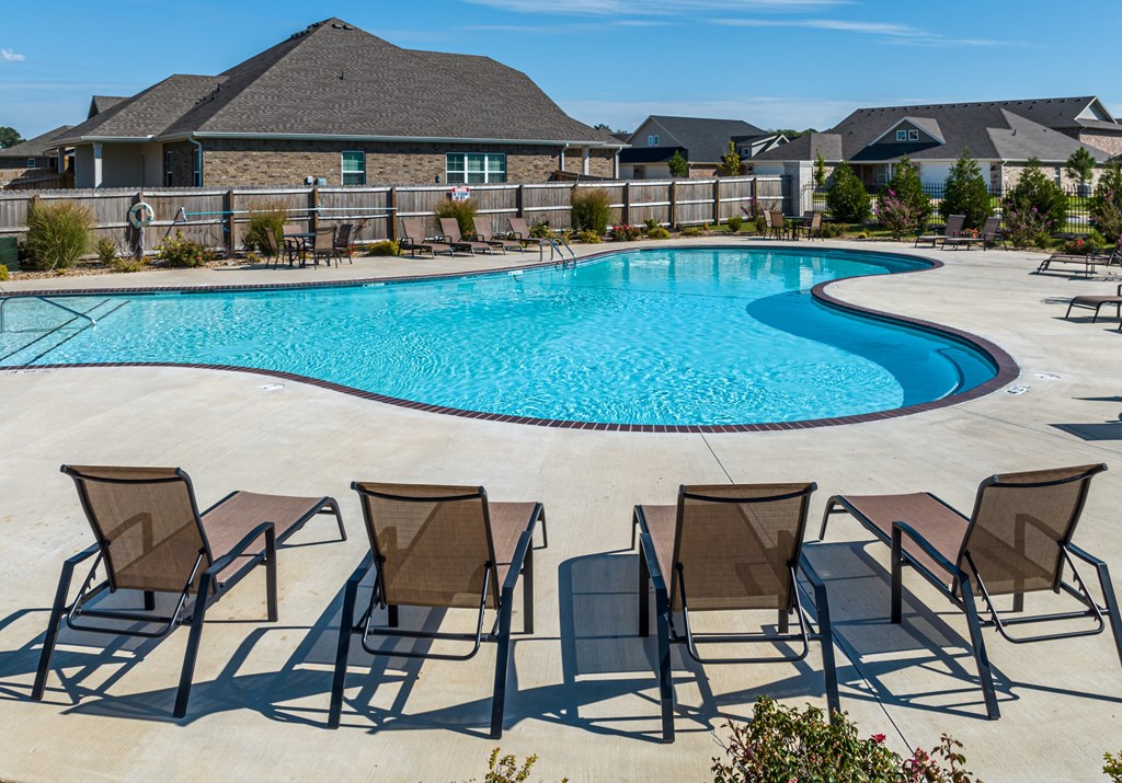 A pool surrounded by chairs and a fence at Cedar Crest Apartments, Farmington, AR