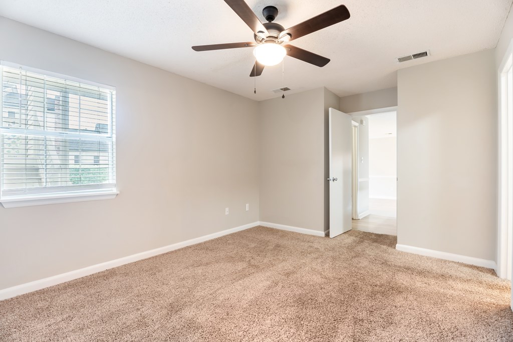 A room with a ceiling fan and carpeted floor. at Rosewood at Colony Square, Rocky Mount, NC