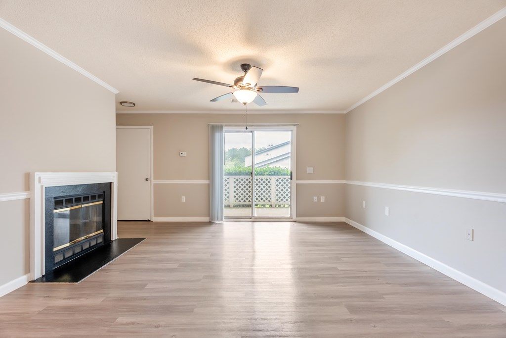 A spacious living room with a fireplace and sliding glass doors leading to a balcony. at Rosewood at Colony Square, Rocky Mount, NC