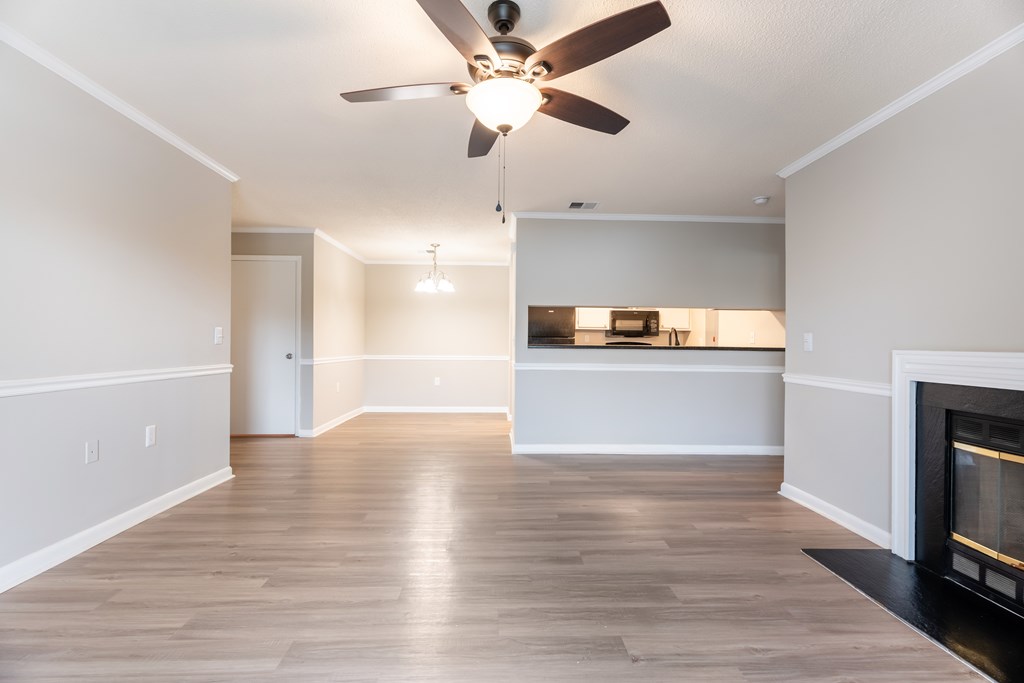 A living room with a fireplace and a ceiling fan. at Rosewood at Colony Square, Rocky Mount, 27804