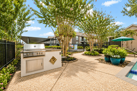 Outdoor grilling station with patio seating area at Woodway Gardens Townhomes Apartments, Texas