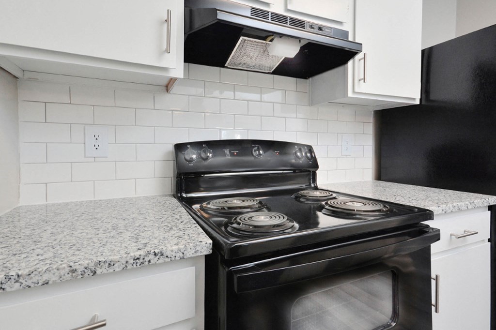 a kitchen with white cabinets and a black stove  at Henley, North Carolina, 28311