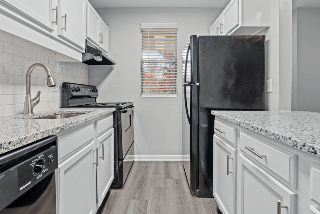 a kitchen with white cabinets and a black refrigerator at The Hudson, Fayetteville