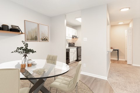 a dining room with a glass table and chairs and a kitchen