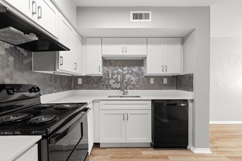 A kitchen with a black stove top oven and white cabinets.