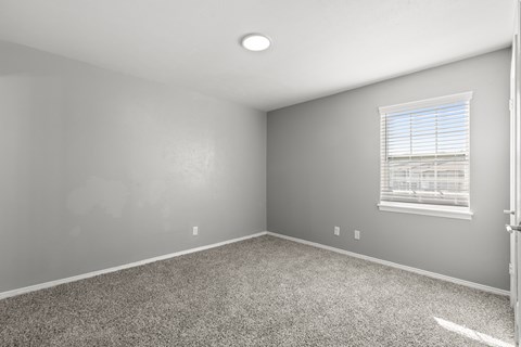 A room with a carpeted floor and a window with blinds.at The Sidney, Sherman Texas
