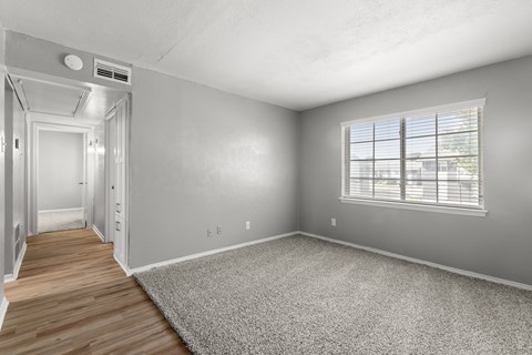 A room with a carpeted floor and a window with blinds.at The Sidney, Sherman, TX 75090