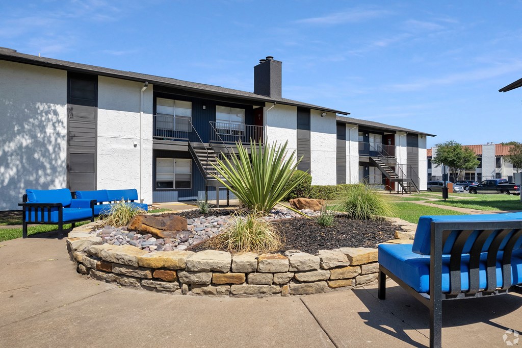 a courtyard with two blue chairs in front of a building
