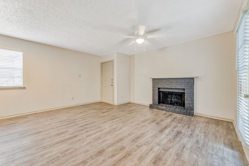 an empty living room with a fireplace and a ceiling fan