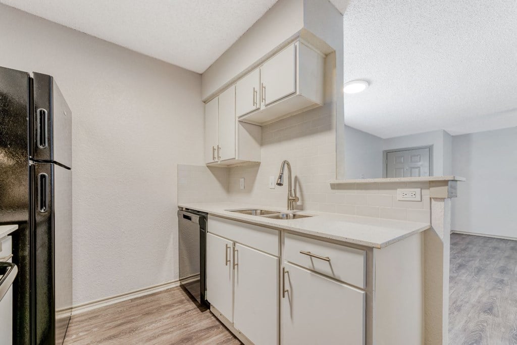 a white kitchen with white cabinets and a black refrigerator