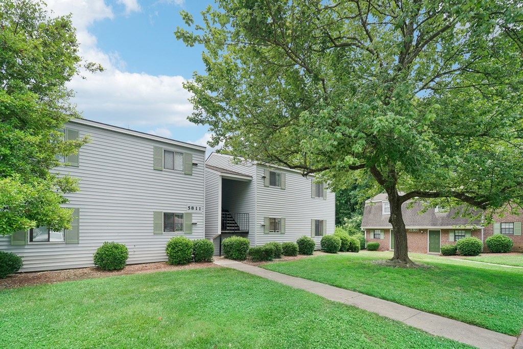 a white house with a tree and a sidewalk