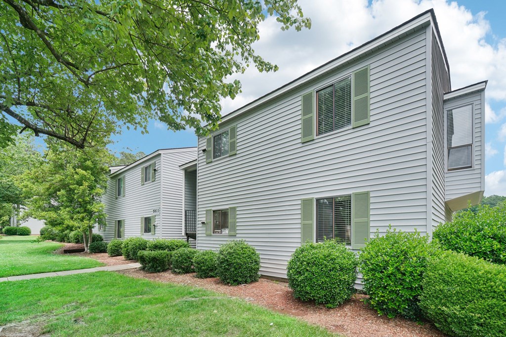 a white house with green bushes in front of it
