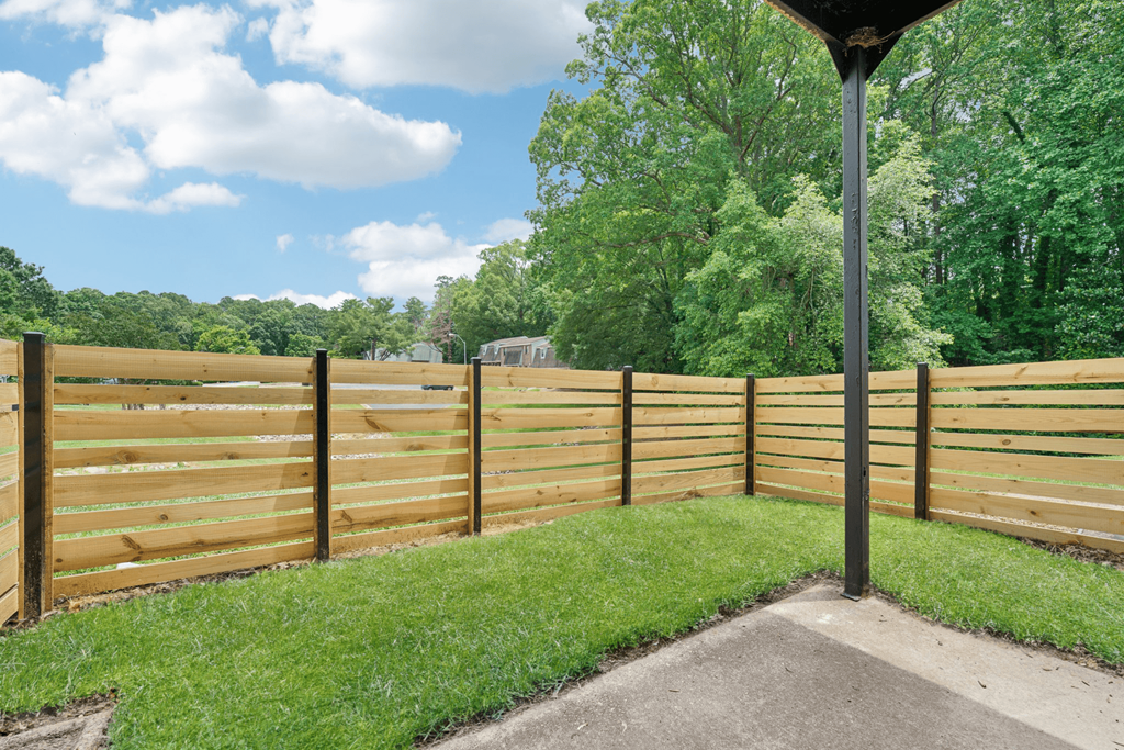 a wooden fence in front of a yard with grass