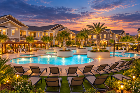 Resort style pool with lounge chairs and palm trees at Echelon at Monterrey Village Apartments, San Antonio, Texas