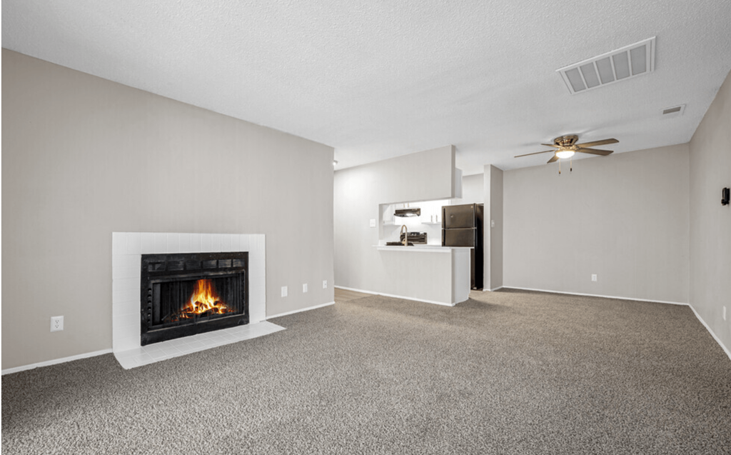 an empty living room with a fireplace and a ceiling fan