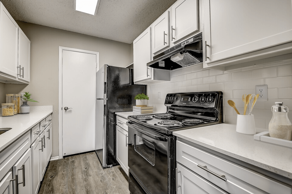 an updated kitchen with white cabinets and black appliances
