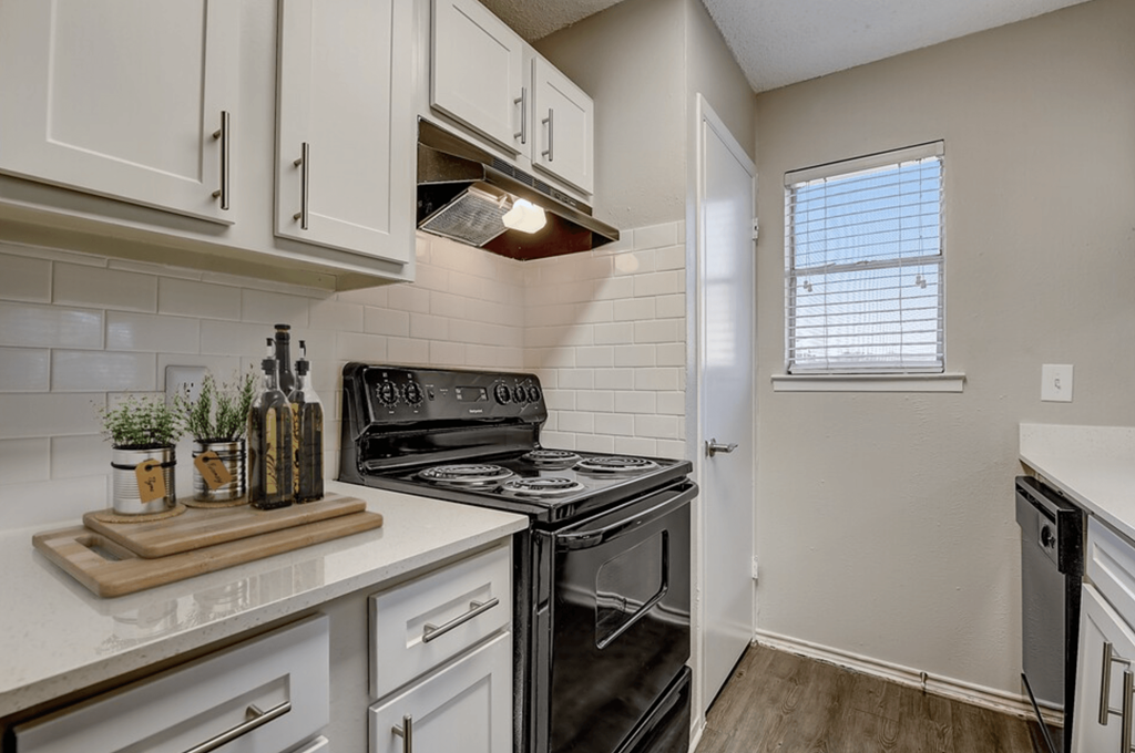 an empty kitchen with white cabinets and a black stove and oven