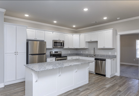 A kitchen with white cabinets and a granite countertop.