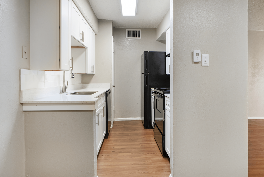 A kitchen with white cabinets and black appliances.