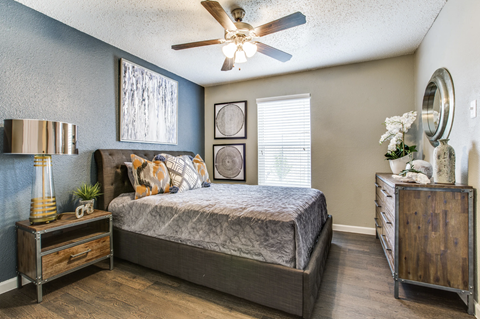 Master bedroom with dark accent wall and wood furniture at The Hangar Apartments, Texas