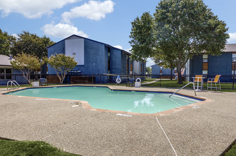 Outdoor pool with concrete deck and safety equipment at The Hangar Apartments, Texas