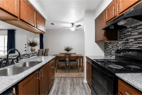 A kitchen with a black stove top oven and wooden cabinets.