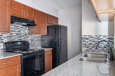 A kitchen with a black refrigerator and a black stove top oven.