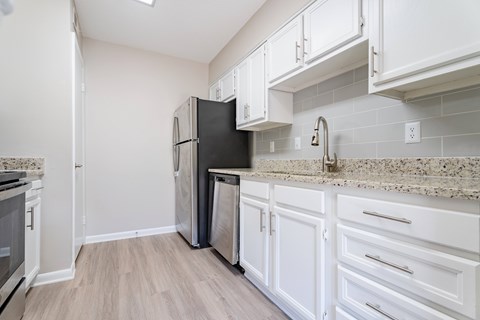 A kitchen with white cabinets and a black fridge.