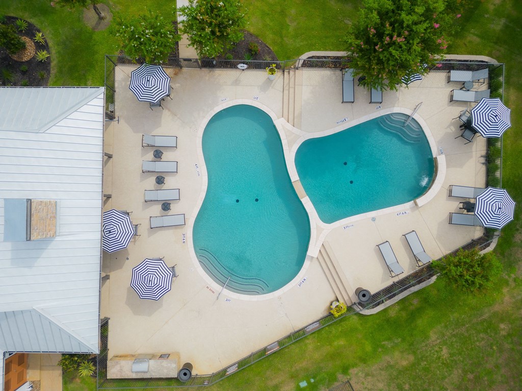 an aerial view of a swimming pool and patio with umbrellas